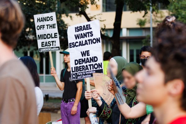 Protesters stand before the steps of City Hall, listening to organizers and guest speakers give first-hand accounts of the tragic effects of political violence in the Middle East.