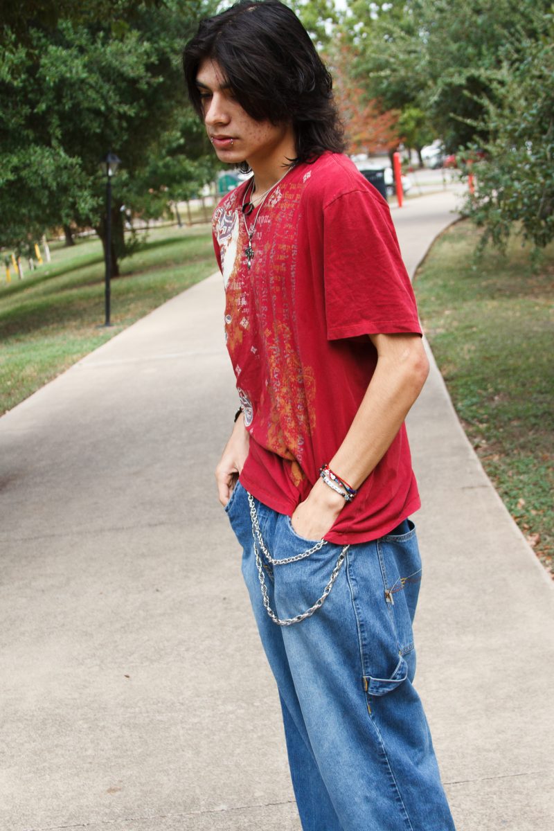 Isaiah Saldivar, a freshman, is seen wearing a Y2K inspired shirt accompanied by a set of jewelry ranging from a striking spike bracelet to necklaces garnering religious iconography. “Well you can’t really shop for these clothes unless you want to pay full price,” Saldivar said. “Usually you go thrifting or I just shop on depop, which is like where people sell vintage clothes or clothes in general.” (Thomas Logan/Hilltop Views)