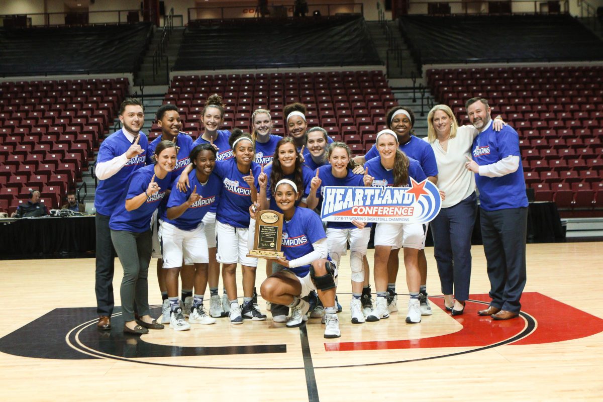 The 2016-17 women's basketball team celebrate their Heartland Conference championship. The season marked the best program record in the Heartland Conference and NCAA DII era, ending with a 20-9 overall and 10-1 at home. Head coach J.J. Riehl (second on the right) still holds the position and now works alongside Khiani Clark (center, back row) and Shakera Barnes (second to the left, middle row).