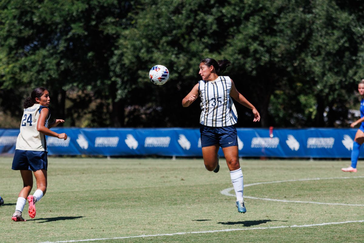 Freshman Annie Rocha prepares a play mid air. Even though this is Rocha’s first collegiate season, she leads the team in goals made, scoring six in the eight games she has played so far. Rocha scored both goals this game.