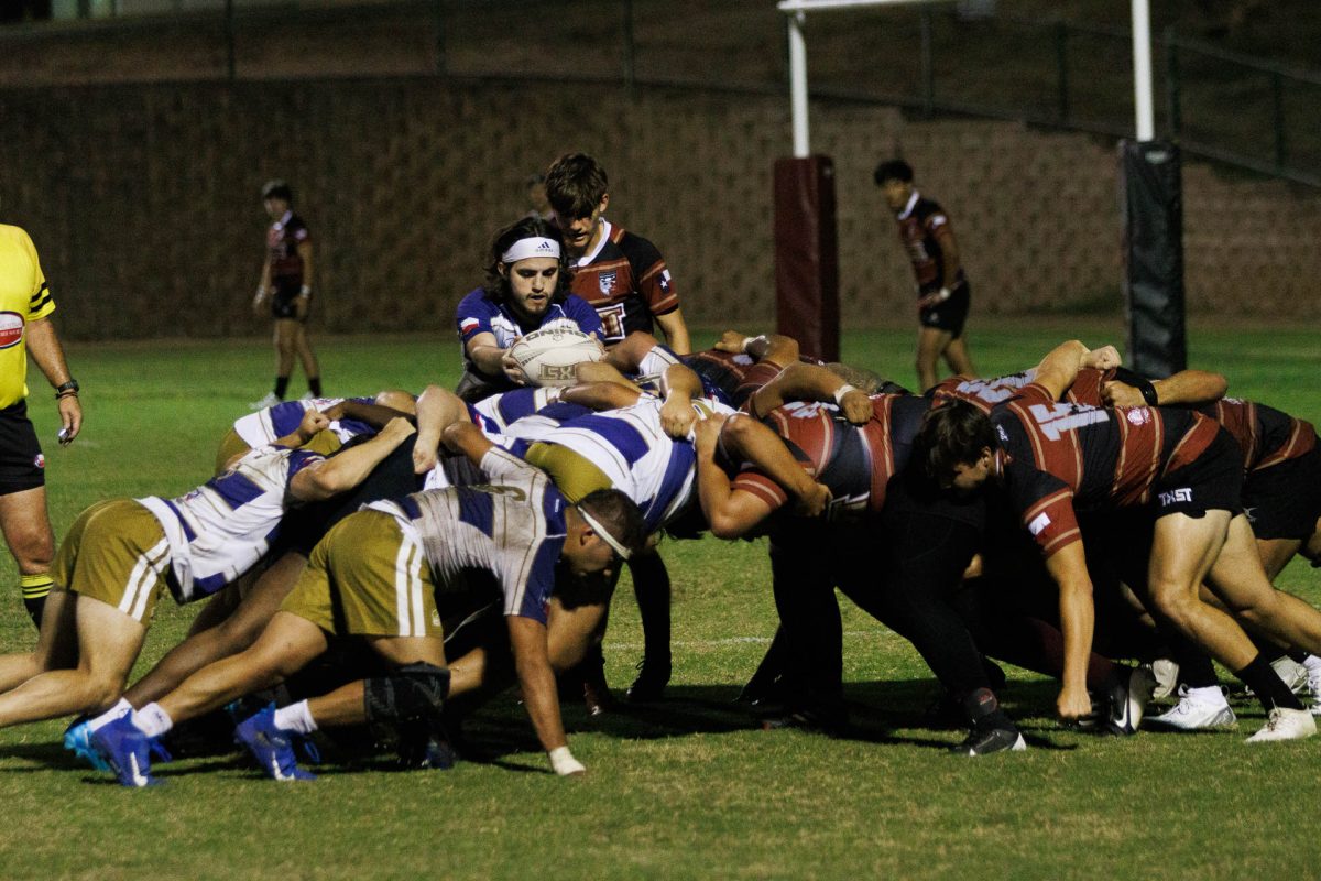 Throughout the game, the Texas State and St. Edward’s teams engaged in scrums. Scrums are the main method for the game to be initiated, where eight players from each team bind together to gain possession of the ball. At the center stands the scrum halves who place the ball in the middle of the scrum then move to the back of each side. If they receive the ball, they then pass it to their other teammates. Pictured center of the scrum is St. Edward’s player Louis Werling substituting for William Perrins.