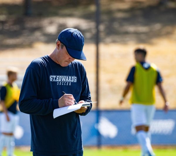 St. Edward's head coach Brian Young, a former University of New Hampshire player and Brown University assistant coach, takes notes during practice. After nearly two decades leading the Hilltoppers, from 2004-2022, Young returned to rebuild the program following its reinstatement, earning the Lone Star Conference Coach of the Year for the team's remarkable turnaround in 2024.