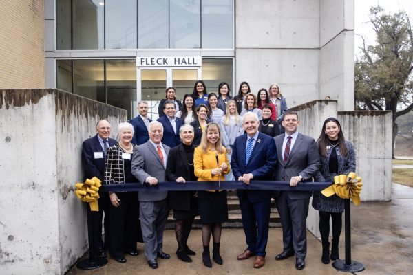 The speakers from the grand opening ceremony gathered around the navy blue ribbon as Fuentes prepared to cut it and officially open the school. 