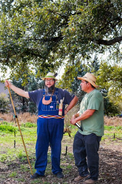 Doug Martin of the Cherokee culture group (left) gestures while speaking with Roy Johnson, campus sustainability coordinator and arborist, at the Cherokee corn celebration on March 8.